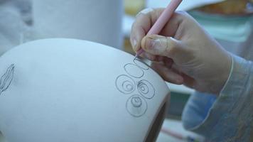 lavorando in un laboratorio di ceramica disegnando e dipingendo un enorme uovo pasquale video