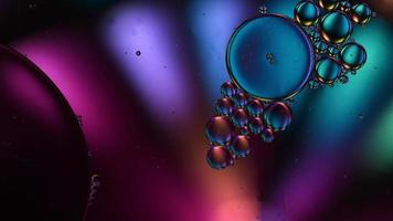 óleo de comida colorido abstrato deixa cair bolhas e esferas fluindo na superfície da água, macro videografia video