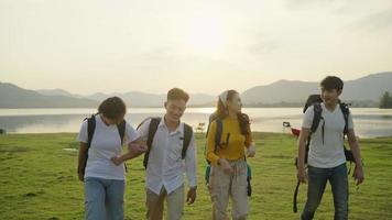 quatre jeunes hommes et femmes asiatiques marchent avec un sac et discutent joyeusement et joyeusement sur le terrain de la tente, le concept de camping et les vacances d'adolescents de style de vie voyageant. video