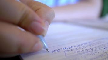 cierre la mano de una mujer sentada en el escritorio sosteniendo un bolígrafo tomando notas en un libro, una mujer de negocios escribe ideas y planes de negocios de inicio en casa, pensamientos creativos en un cuaderno. creando el concepto de lista video