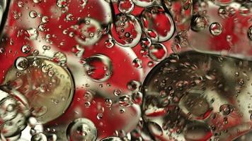 olio di cibo colorato astratto gocce bolle e sfere che scorrono sulla superficie dell'acqua, videografia macro