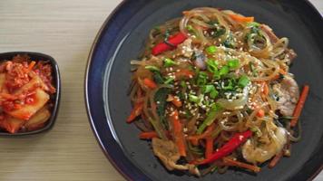 japchae of geroerbakte Koreaanse vermicelli noedels met groenten en varkensvlees gegarneerd met witte sesam - Koreaanse traditionele voedselstijl video