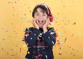 smiling child with confetti Wearing Christmas Santa Claus Hat photo