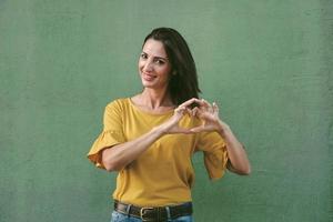 mujer joven sonriente que muestra el corazón con las manos foto