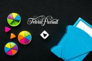 juego de mesa negro de búsqueda trivial con troquel blanco, piezas de plástico de colores y tarjetero azul foto