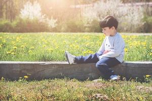 thoughtful child sitting on field photo