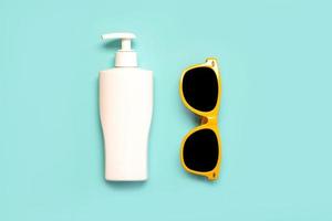 Summer holiday concept.Top view of yellow sunglasses and bottle of sunscreen photo