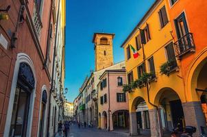 calle con viejos edificios coloridos con bandera italiana en la pared y la torre en el centro histórico medieval de padua foto