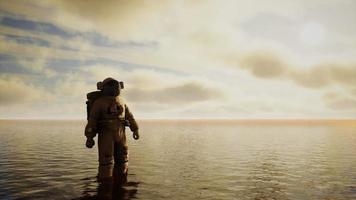 Spaceman in the sea under clouds at sunset video