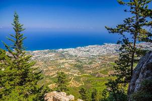 Aerial view of Kyrenia District valley with Kyrenia Girne city and Mediterranean sea in sunny day, green trees on rock of Kyrenia Girne mountains photo