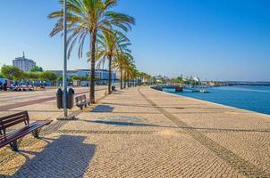 Ribeirinha de Portimao town, cobblestone embankment promenade of Arade River in city centre with palm trees photo
