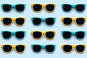 Top view of creative pattern made of blue and yellow sunglasses photo