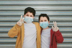 two kids with medical mask doing victory sign photo