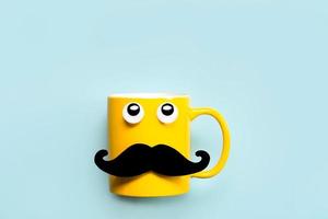 Happy Father's Day.Yellow mug with mustache and funny eyes looking up and copy space photo