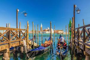 Gondolas moored docked at wooden pier in water of San Marco basin