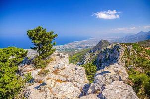 Aerial view of Kyrenia District valley with Kyrenia Girne city and Mediterranean sea in sunny day, green trees on rock of Kyrenia Girne mountains photo