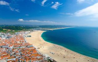 Portugal, panoramic view of Nazare in summer, mountain landscape with dense greenery in the background, Nazare coastline