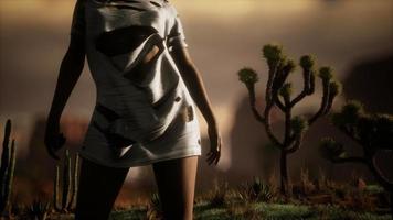 mujer con camisa rota parada junto a cactus en el desierto al atardecer video