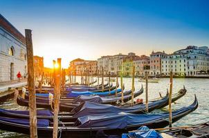 Gondolas moored docked on pier of Grand Canal waterway in Venice photo