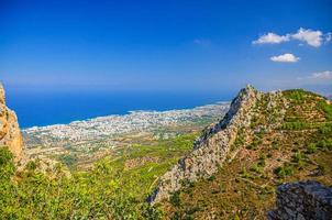 Aerial view of Kyrenia Girne mountain range and valley in front of Mediterranean sea, green trees on rock foreground photo