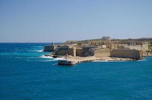 vista de la entrada del puerto con faro, valletta, malta foto