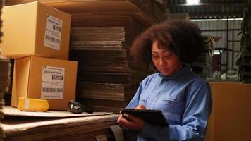 African American female worker in safety uniform using bar code scanner to check shipment orders at parcels warehouse, paper manufacture factory for the packing industry, logistic transport service. video