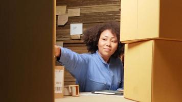 African American female worker in safety uniform using bar code scanner to check shipment orders at parcels warehouse, paper manufacture factory for the packing industry, logistic transport service. video