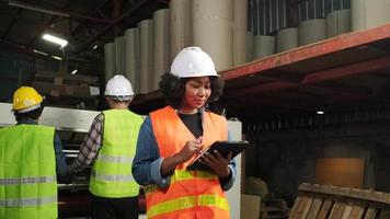 African American female engineer worker in safety uniform and hard hat, quality inspect by tablet, maintenance, check the machine at paper production manufacture industry, factory technician manager. video