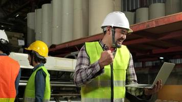 ingegnere asiatico maschio in uniforme di sicurezza e elmetto con laptop celebra, mano alzata, felice e allegro, lavori industriali di successo, risultati, fabbrica di produzione di tecnici professionisti. video