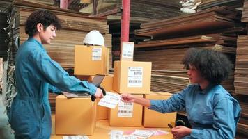 Two safety uniform female workers and colleagues use bar code scanner to check shipment orders stock at parcels warehouse, paper manufacture factory for packing industry, logistic transport service. video