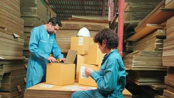deux travailleurs et collègues en uniforme de sécurité utilisent un lecteur de codes à barres pour vérifier le stock des commandes d'expédition dans l'entrepôt de colis, l'usine de fabrication de papier pour l'industrie de l'emballage, le service de transport logistique.