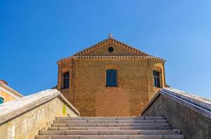 escaleras del puente de piedra de ladrillo a través del canal de agua y la iglesia católica de san domenico en chioggia foto