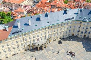 vista superior de la plaza del patio del castillo de praga y el antiguo palacio real con pequeñas figuras de gente caminando foto