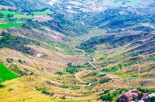 Aerial top panoramic view of landscape with path in valley, green hills, fields and forests of Republic San Marino photo