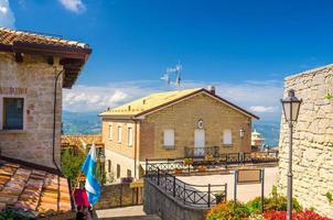 Typical yard with traditional buildings and houses with brick stone walls, flowers, San Marino flag photo