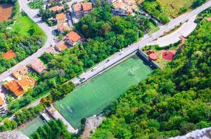 Top view from above of football stadium green grass lawn field and trees photo