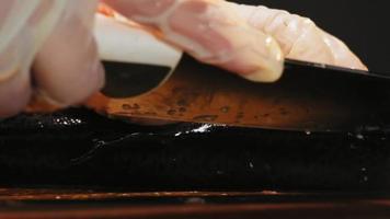 Woman in latex gloves cuts back of delicious red fish with sharp knife to prepare dish on board extreme closeup slow motion video