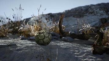 uma velha bola de futebol rasgada jogada encontra-se na areia da praia do mar video