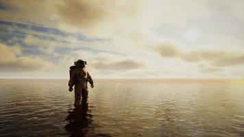 Spaceman in the sea under clouds at sunset video