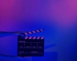 Hand holds empty film making clapperboard on color background in studio photo