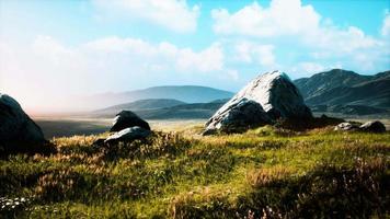 meadow with huge stones among the grass on the hillside at sunset video