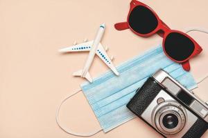 Protective surgical mask with sunglasses,retro photo camera and airplane with copy space.Travel concept with covid-19