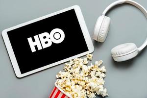 HBO logo on the screen of a white digital tablet with popcorn and white headphones photo