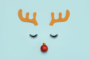 Merry Christmas.Christmas Rudolph reindeer horns with false eyelashes and red christmas ball.Christmas concept background