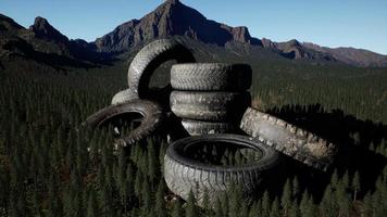 Konzept der Umweltverschmutzung mit großen alten Reifen im Bergwald