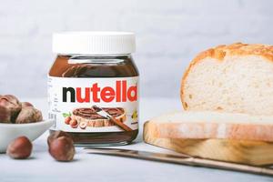 tarro de nutella con rebanadas de pan y avellanas sobre una mesa foto