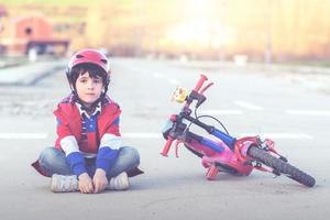 niño sentado en el suelo con bicicleta foto