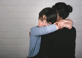 Sad child hugging his mother photo