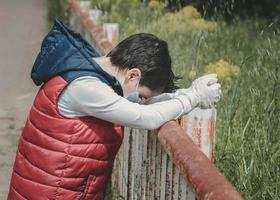 Coronavirus,sad and thoughtful kid wearing medical mask photo