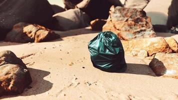 sac poubelle en plastique noir plein de déchets sur la plage video